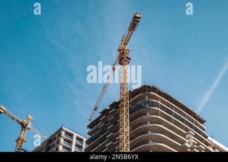 Crane and building construction site against blue sky. Industry of housing new buildings. Industrial concept Stock Photo