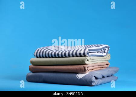 Stack of clean bed sheets on blue background Stock Photo