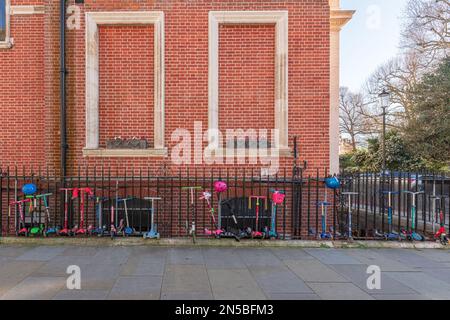 Childrens Scooters lined up against the railings outside The Knightsbridge School, Lennox Gardens, London, SW1. Stock Photo