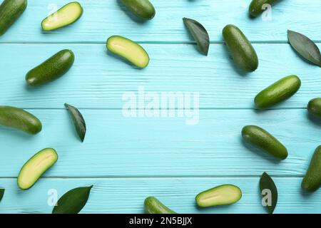 Frame made of fresh seedless avocados with green leaves on turquoise wooden table, flat lay. Space for text Stock Photo