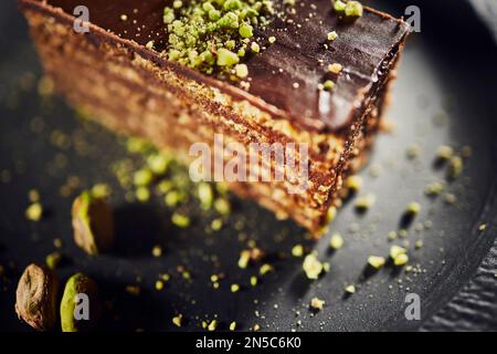 Chocolate cake with walnuts and pistachio isolated on black background. Pastry from homemade bakery Stock Photo