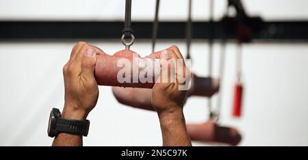 Male participant in an obstacle course doing suspension exercises, obstacle course race ocr Stock Photo