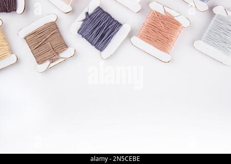 Skeins of cotton threads of different colors lie at the top of the frame on a white background Stock Photo
