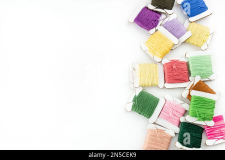 Skeins of cotton threads of different colors lie on the right side of the frame on a white background Stock Photo