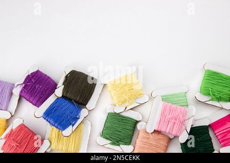 Skeins of cotton threads of different colors lie at the bottom of the frame on a white background Stock Photo