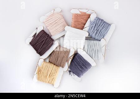 Skeins of cotton threads of different colors lie in a pile on a white background Stock Photo