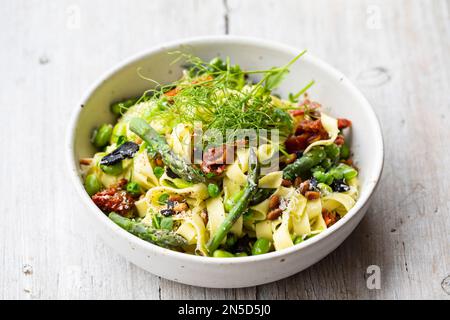 Tagliatelle pasta with asparagus, green peas and broad beans Stock Photo