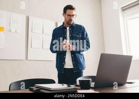 Young businessman talking to his team during an online meeting. businessman having a video conference on a laptop. businessman with eyeglasses working Stock Photo