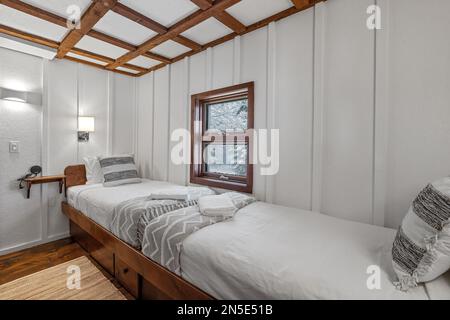 Two small beds in a white bedroom next to each other Stock Photo