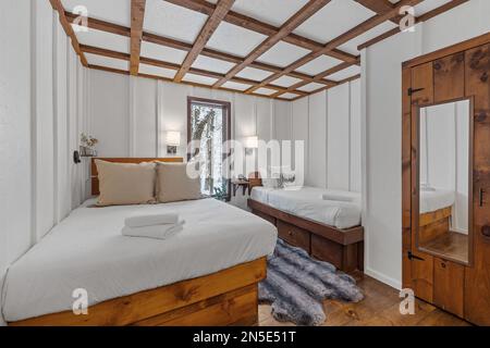 A king size bed and small bed in a white bedroom next to each other Stock Photo