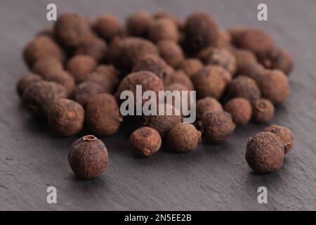 natural allspice in peas on a stone gray plate Stock Photo