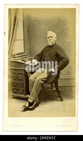 Original older Victorian era CDV (carte de visite or visiting card) of gentleman sitting at a desk, wearing a sack coat (for informal day wear) from the studio of F Spalding, Tindal Square, Chelmsford, Essex, U.K. Fred Spalding senior started the family business in 1862.  Circa late 1860's Stock Photo