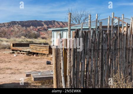 Abandoned house behind a wooden pole fence with desert mountains in the background Stock Photo