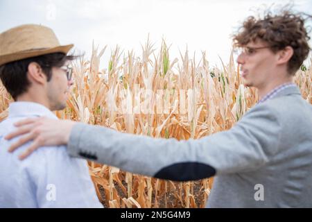 An insurance agent talking to a farmer in the fields, focus on the fields, people out of focus. Stock Photo