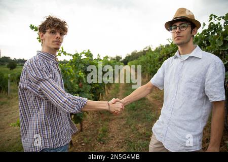 Two winemakers shaking hands, partnership between farmers in the vineyard. Stock Photo