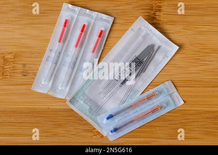 A top down portrait of multiple packages of different acupuncture needles, ready to use on someone with health issues. There are also plastic tubes in Stock Photo