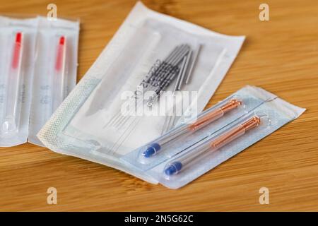 A close up portrait of multiple packages of different acupuncture needles, ready to use on someone with health issues. There are also plastic tubes in Stock Photo