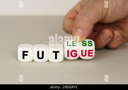 On a gray surface are white cubes with the inscription - fatless to fatigue. Two dice in hand. Medical concept. Stock Photo