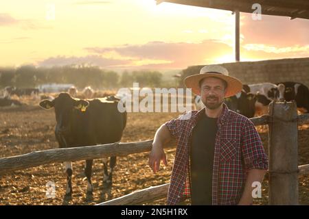 Worker standing near cow pen on farm. Animal husbandry Stock Photo