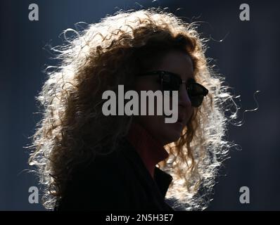 09 February 2023, Hesse, Frankfurt/Main: The curly hair of a woman waiting on a street downtown glows in the backlight. Photo: Arne Dedert/dpa Stock Photo