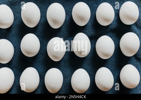 Close up of fresh store bought white eggs on blue kitchen towel Stock Photo