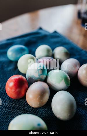 Close up of dyed Easter eggs sitting on blue towel on table Stock Photo