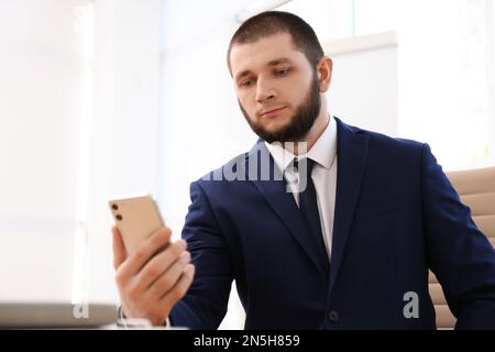Man unlocking smartphone with facial scanner indoors. Biometric verification Stock Photo