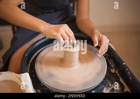 Girl hands working with clay on a Potter's wheel close up. Tradi Stock Photo