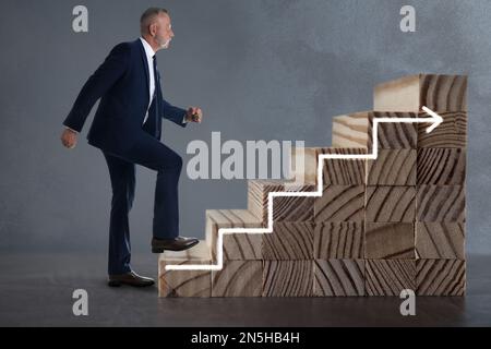 Businessman walking up stairs against grey background. Career ladder concept Stock Photo