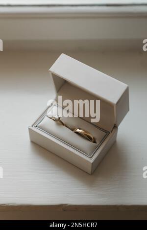 Golden wedding rings in white ring box, on white wooden surface Stock Photo