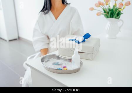 Young brunette woman in a white coat makes medical procedures, waiting for nurse to take blood or puts a dropper on the patient. Medical services and Stock Photo