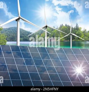 Alternative energy sources. Wind turbines installed in water, solar panels on foreground Stock Photo