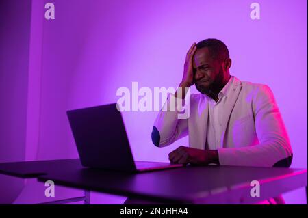 angry man at work. angry african american worker looking at laptop screen with software problems. Stock Photo