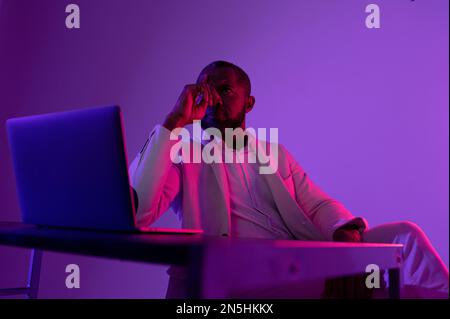Photo of pensive man in white suit thinking about new web security project in night office near computer Stock Photo