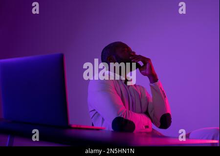 Photo of pensive man in white suit thinking about new web security project in night office near computer Stock Photo