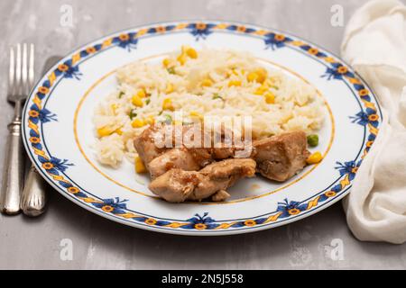 chicken fillet baked with sauce and boiled rice with vegetables on plate Stock Photo
