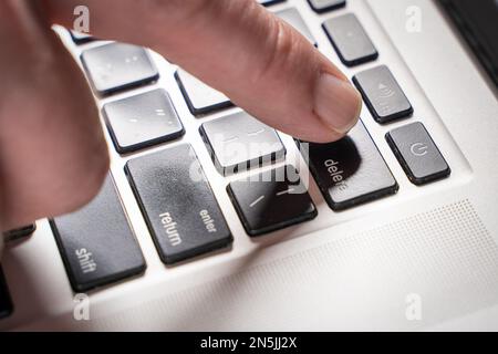Finger is pressing delete key of computer keyboard Stock Photo