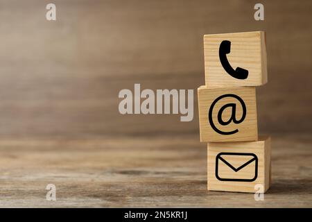 Hotline service. Cubes with icons on wooden background, space for text Stock Photo