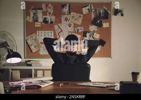 Detective looking at evidence board in office, back view Stock Photo