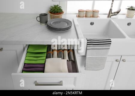 Open drawer with different folded towels and napkins in kitchen Stock Photo
