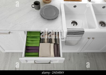 Open drawer with different folded towels and napkins in kitchen, above view Stock Photo