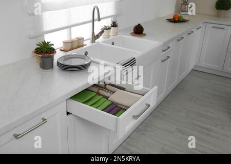 Open drawer with different folded towels and napkins in kitchen Stock Photo