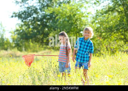 Cute little children with butterfly net outdoors. Spending time in nature Stock Photo