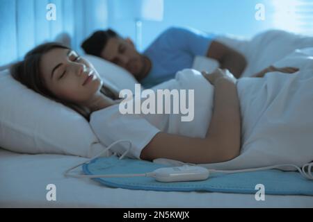 Couple sleeping on electric heating pad in bed at night Stock Photo