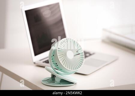 Modern electric fan and laptop on table in office Stock Photo