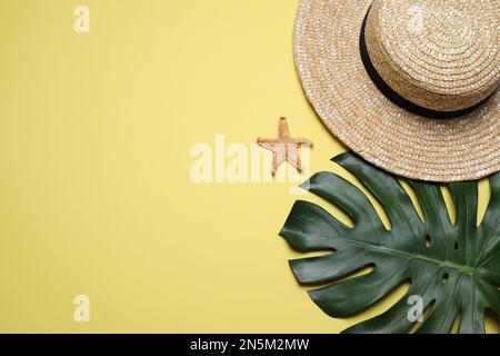 Straw hat, tropical leaf and starfish on yellow background Stock Photo