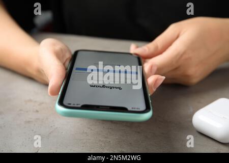 MYKOLAIV, UKRAINE - JULY 9, 2020: Woman using Instagram app on Iphone 11 at table, closeup Stock Photo