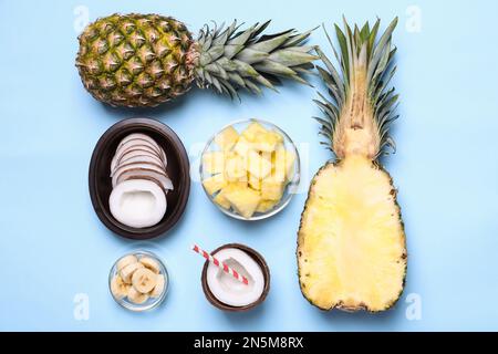 Flat lay composition with pineapples and coconuts on light blue background Stock Photo