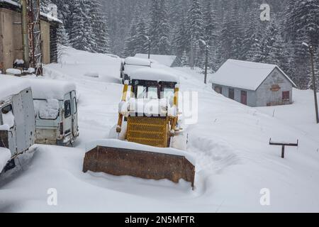 The tractor is covered with a thick layer of snow. The old vehicles are covered in snow Stock Photo