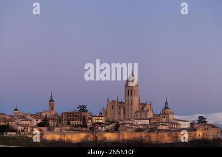 Segovia, Spain - 4 January 2022: Panoramic view of Segovia with the towers of cathedral at sunset with purple sky in winter with Guadarrama Mountains Stock Photo